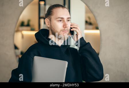 A young business man with a beard is talking on a smartphone. Stock Photo