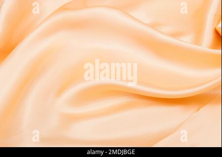 Abstract background with folds of peach-beige silk Stock Photo