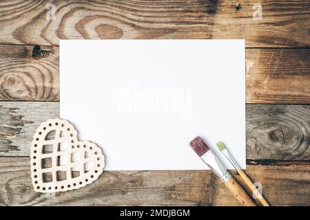 Blank sheet of paper and brushes for drawing on a wooden background, flat lay. Stock Photo