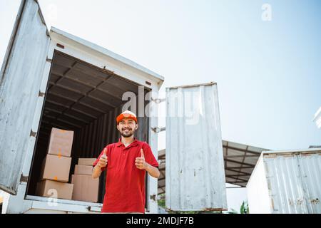 warehouse workers in red smiling with thumbs up Stock Photo