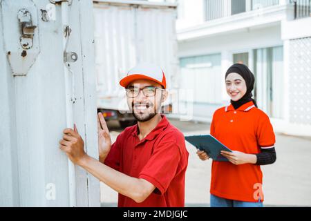 male worker in red uniform closing container door Stock Photo