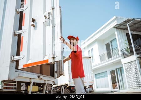 warehouse workers in red closing the door of a container Stock Photo