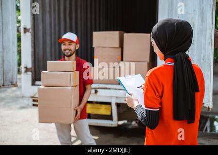 female worker with notes checking the package by delivery man Stock Photo