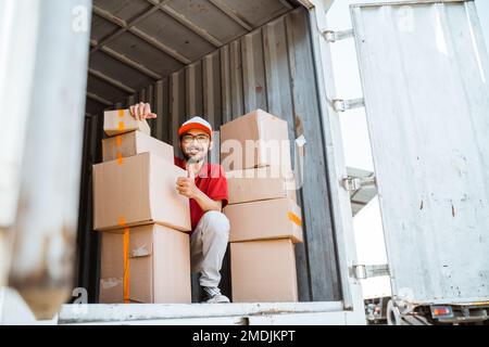 delivery man with thumbs up working unloading boxes from containers Stock Photo