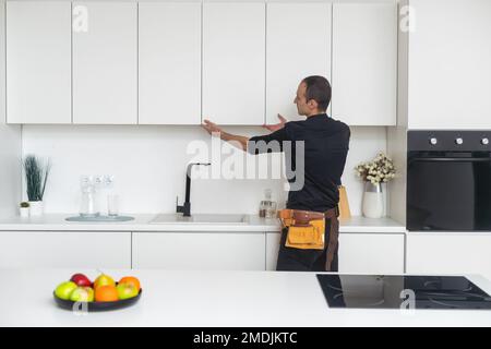 Young Handyman In Overall Installing Drawer In Kitchen Stock Photo
