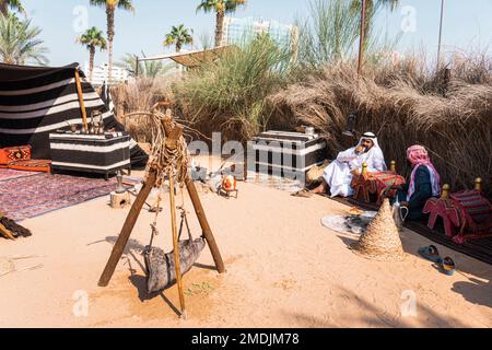 two Arabs are sitting near a campfire drinking coffee and they talk. Dubai, United Arab Emirates. Dubai, UAE. November 27, 2022 Stock Photo
