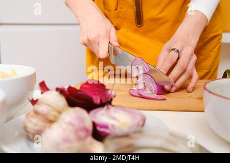 Closeup view of female hands cutting onion into slices Stock Photo