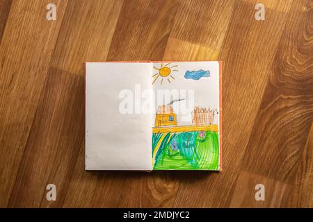 children's drawing a drawn house with flowers under the sun in a notebook, children's dream home drawn by a child, children's drawing Stock Photo