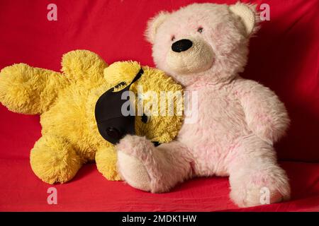 children's soft plush toys in medical mask lie on the red sofa, healthcare and medicine, children's morbidity Stock Photo