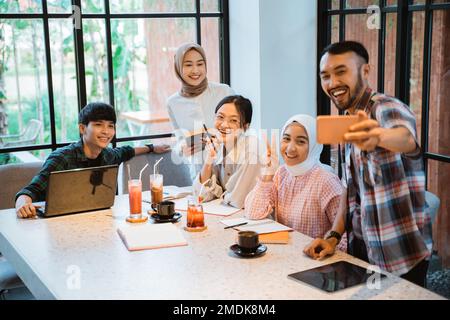 five young asian people smiling taking selfie using cell phone Stock Photo