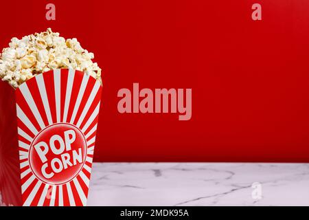 Salted popcorn scattered on white marble and red background with copy space Stock Photo
