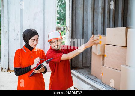 two young workers in red uniforms manage boxed products Stock Photo