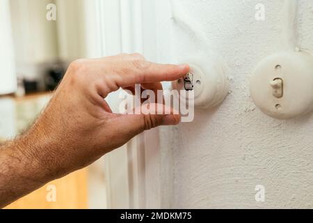 Male hand pushing old retro light switch in living room, selective focus Stock Photo