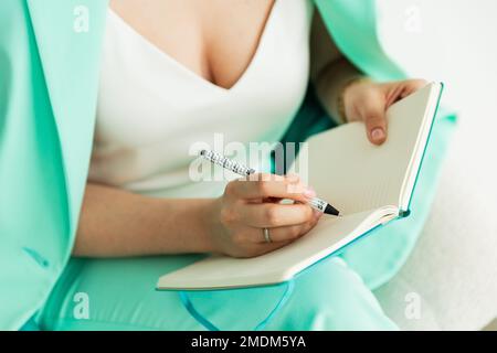 girl writes in notepad, mint color, close up Stock Photo