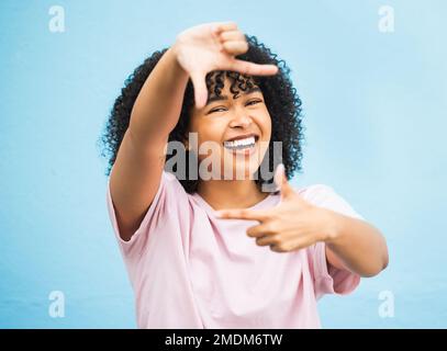 Black woman, hands and smile for frame, picture perfect or photo against a blue studio background. Portrait of African American female, person or lady Stock Photo