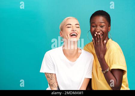 Best friends make you laugh a lot harder. Studio shot of two happy young women posing together against a turquoise background. Stock Photo