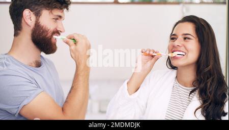Who said routine has to be boring. a happy young couple brushing their teeth together at home. Stock Photo