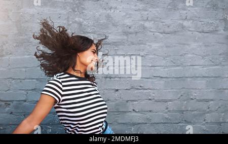Dance is my freedom. a young woman dancing against a grey wall. Stock Photo