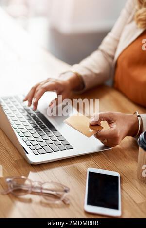 Online baking is the safe and easy way to go. an unrecognizable businesswoman using a laptop and credit card to purchase online in her office. Stock Photo