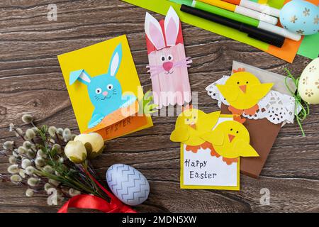 Easter congratulation cards with Easter bunny and chickens on a wooden table. Copy space. Handmade. Project of children's creativity, handicrafts, cra Stock Photo