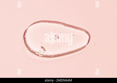 Transparent Liquid gel cosmetic smudge texture. Clear liquid gel with bubbles drop isolated on pink background Stock Photo
