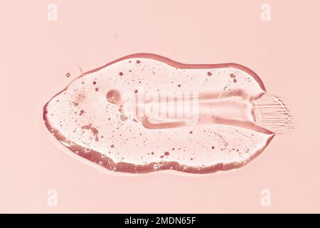 Liquid gel smear isolated on pink background. Beauty cosmetic smudge lotion, facial jelly serum, cleanser, shower gel or shampoo Stock Photo