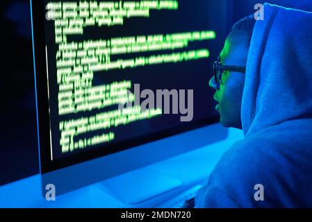 Hes one hack away from his end goal. a young male hacker cracking a computer code in the dark. Stock Photo