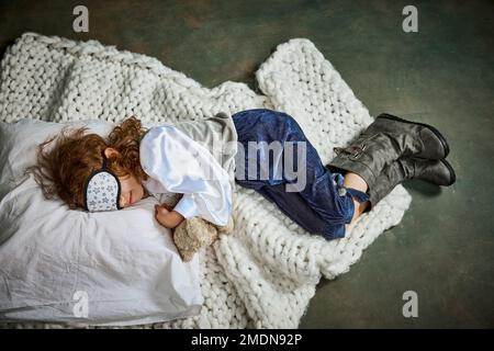Ariel view of cute little girl in clothes sleeping on white blanket. Concept of napping day, dreams, happy childhood. Stock Photo