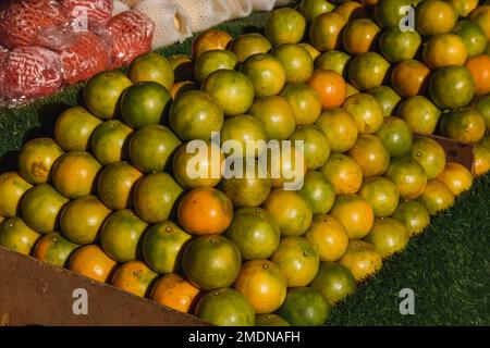 Pile of green oranges and mandarins for sale at a street market in Ko Lanta, Krabi, Thailand. Stock Photo