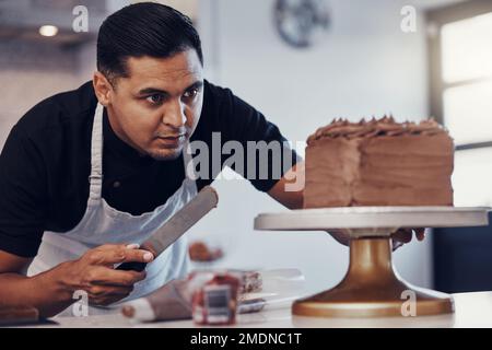 Baking, kitchen and man icing cake with chocolate frosting and piping bag in bakery with focus and skill. Sweets, small business and baker decorating Stock Photo