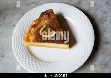 Slice of Lemon Cheesecake on round ceramic plate on the marble table. Stock Photo