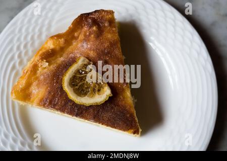 Slice of Lemon Cheesecake on round ceramic plate on the marble table. Stock Photo