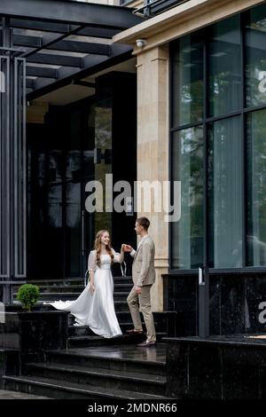 The groom gives his hand to the bride walking down the stairs. Shooting on the wedding day. Stock Photo