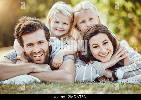 Family, park and outdoor portrait of parents and girl children with love and care in nature. Mother, dad and kids with a smile in summer feeling happy Stock Photo