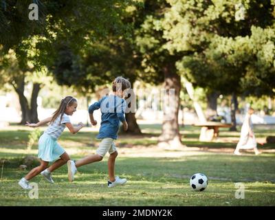 Whos going to be the next football star. an adorable little boy and girl playing soccer in the park. Stock Photo
