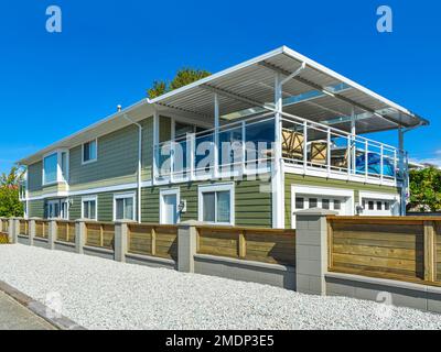 New residential house with wooden fence along a road Stock Photo