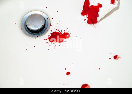 Red blood drops in white bathroom sink. Real blood as traces and evidence of a crime. Concept of nosebleed, injury, violence, murder or suicide. DNA. Stock Photo