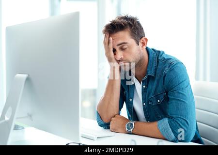 I feel so out of it today. a young businessman looking overly stressed out in his office. Stock Photo