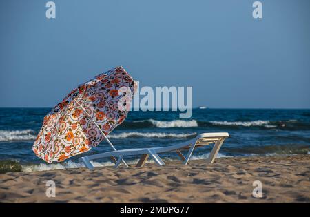 Beach umbrella from the sun and sunbeds are on the beach against the blue sea, sunbeds are towels. Stock Photo