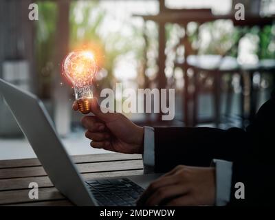Inspiration and creative management concepts. Many gears working inside creative idea light bulb holding by businessperson hand who working with lapto Stock Photo