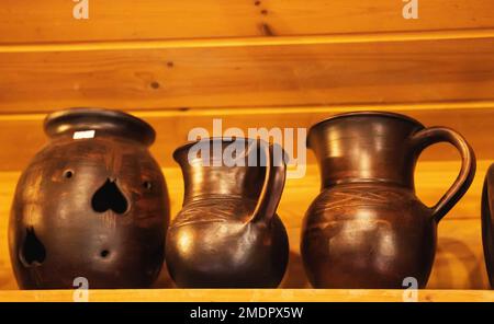Beautiful brown earthenware jugs stand on a shelf. Ware from ceramics and clay. Close-up Stock Photo
