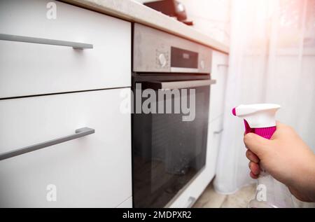 Cleaning a modern oven with a special cleaner. Caring for the oven door and panel, close-up Stock Photo