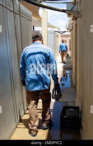 Bryan Anderson (left) and William Moody (right), heating, ventilation, and air conditioning (HVAC) technicians with Facilities Maintenance Branch, Public Works Division (PWD), Marine Corps Air Ground Combat Center (MCAGCC), walk to their repair trucks after operating on an air conditioning at MCGACC, Twentynine Palms, California, July 22, 2022. Despite the extreme heat of the high desert, the PWD, HVAC section maintains performance of air-cooling systems on buildings at the Combat Center. Stock Photo