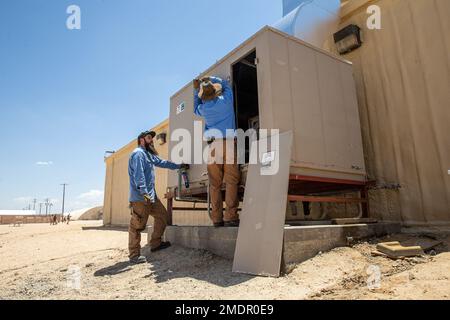 Bryan Anderson (left) and William Moody (right), heating, ventilation, and air conditioning (HVAC) technicians with Facilities Maintenance Branch, Public Works Division (PWD), Marine Corps Air Ground Combat Center (MCAGCC), operate on an air conditioning unit at MCGACC, Twentynine Palms, California, July 22, 2022. Despite the extreme heat of the high desert, the PWD, HVAC section maintains performance of air-cooling systems on buildings at the Combat Center. Stock Photo