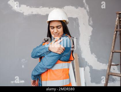 Construction worker holds shoulder in pain from workplace injury on site Stock Photo