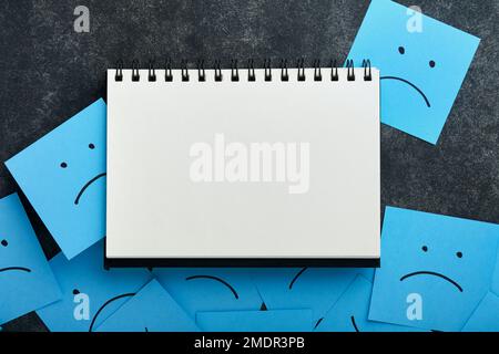 Blue sticky notes blank with drawing sad face on black background with copy space ready for your message. Blue Monday and mental health concept idea. Stock Photo
