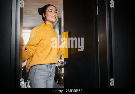 Entrance, creative and Asian woman opening a door to an office at a graphic design startup company. Vision, happy and Japanese designer at a workspace Stock Photo