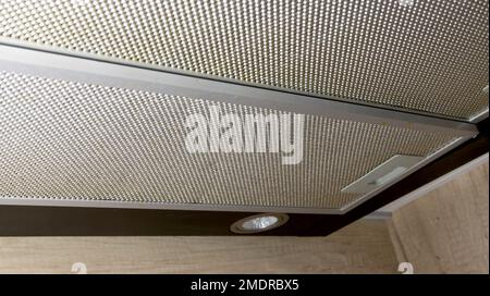 Modern kitchen hood with grease filter for air purification. Replacing the grease filter and maintaining the kitchen hood, technology Stock Photo