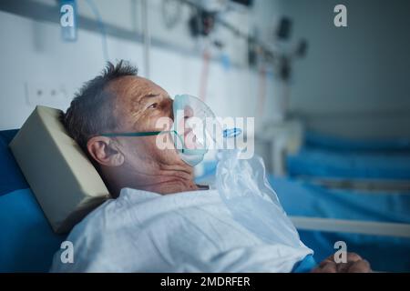 Senior man with oxygen mask lying in a hospital bed. Stock Photo