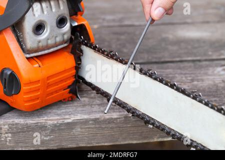 chainsaw chain sharpening with a special file. Dulling an old chain on a chainsaw bar. Stock Photo